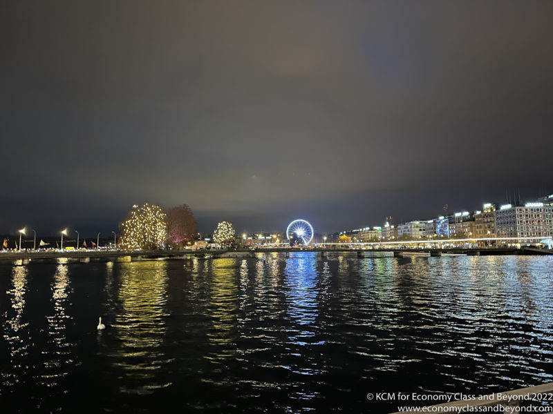 a city skyline with lights and a ferris wheel on the water