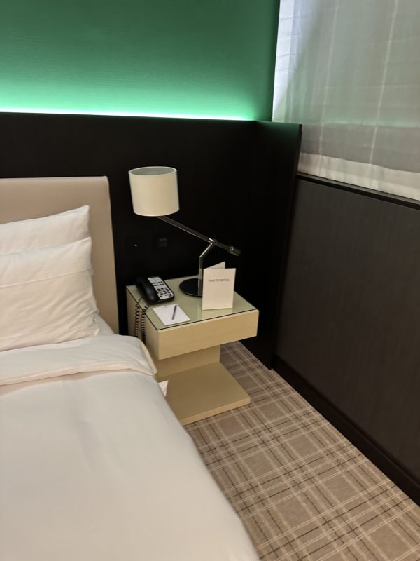a bed with a lamp and a phone on a table