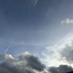 a blue sky with clouds and a jet trail