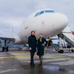 a man and woman standing in front of an airplane