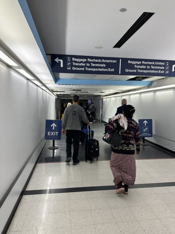 people walking in a hallway with signs and luggage