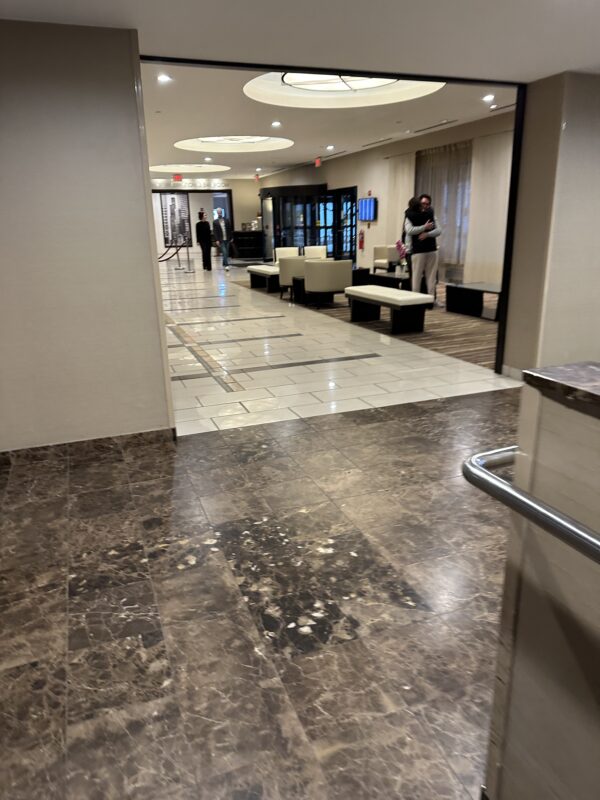 a hallway with a marble floor and a couple of people