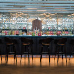 a bar with chairs and a row of bottles