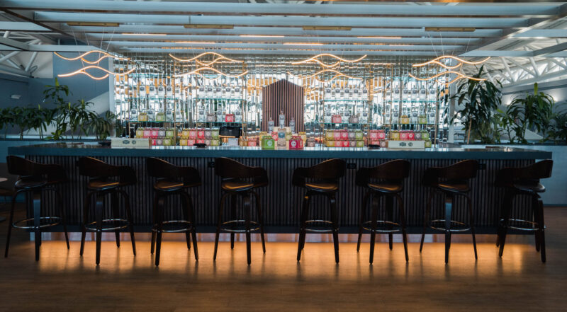 a bar with chairs and a row of bottles