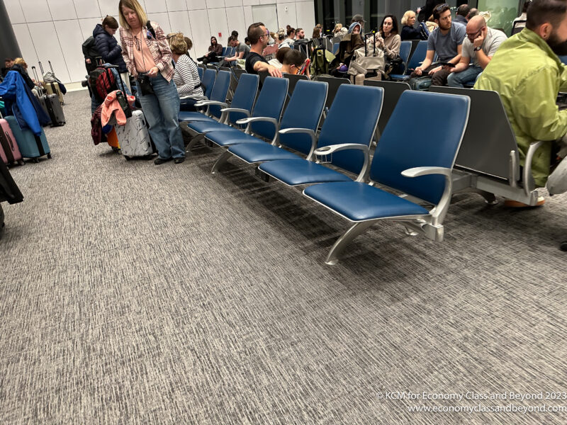 a group of people sitting in a row of blue chairs