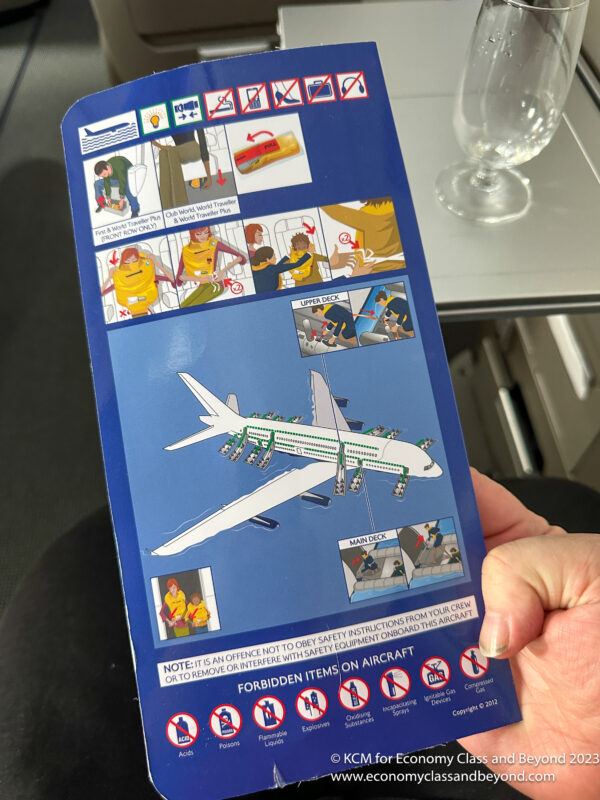a hand holding a blue and white airplane instruction booklet