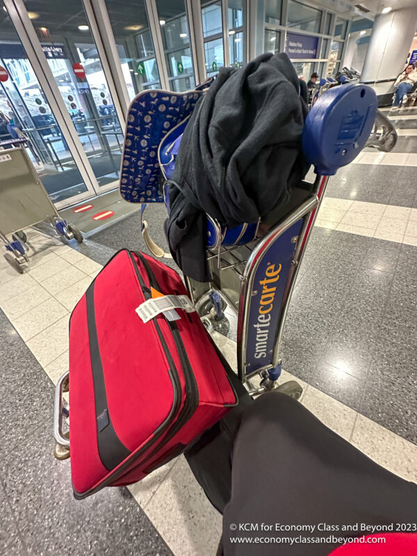 a luggage cart with a person's leg and a jacket on it