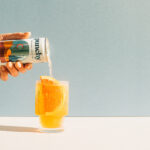 a hand pouring a drink into a glass