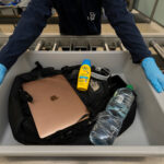 a person in a luggage cart with a laptop and a bottle of water