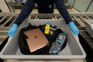 a person in a luggage cart with a laptop and a bottle of water