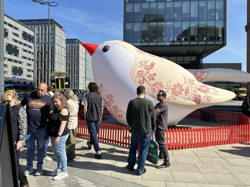 a group of people standing around a large inflatable bird