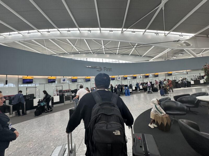 a man with a backpack walking with luggage in an airport