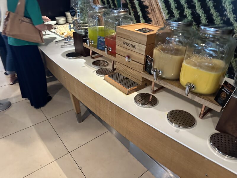 a counter with a row of jars of juice and a person standing behind them
