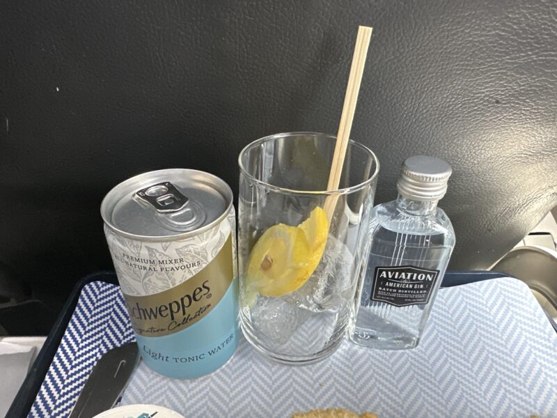 a glass and a can of vodka and a lemon slice on a table