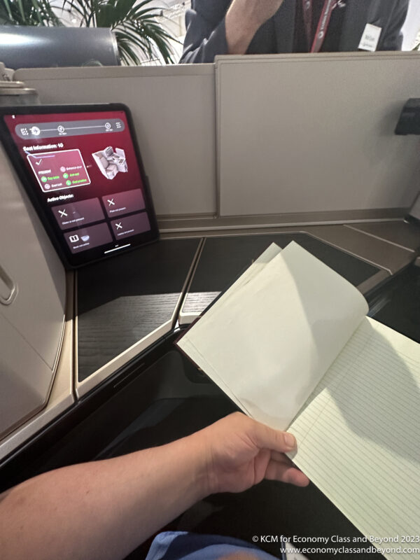 a hand holding a notebook in front of a computer screen