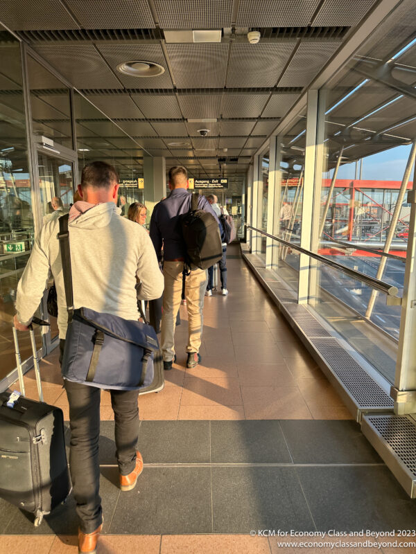 a group of people walking down a hallway with luggage