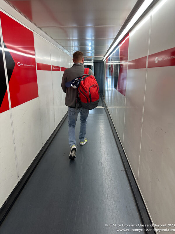 a man walking down a hallway with a backpack