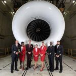 a group of people standing in front of a large white jet engine