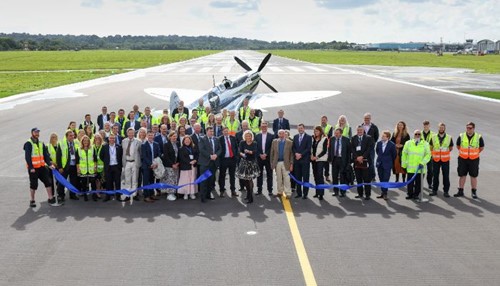 a group of people standing in front of a ribbon on a runway