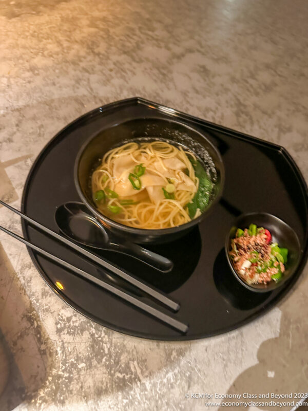 a bowl of soup with chopsticks and a bowl of noodles