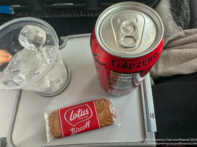 a can of soda and a glass of ice on a tray
