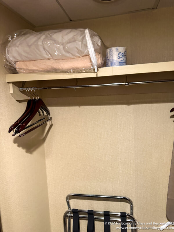 a closet with clothes swingers and a bag of blankets