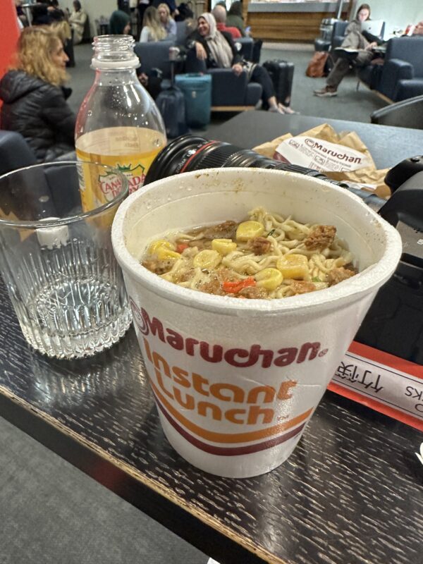 a cup of noodles and a bottle of soda