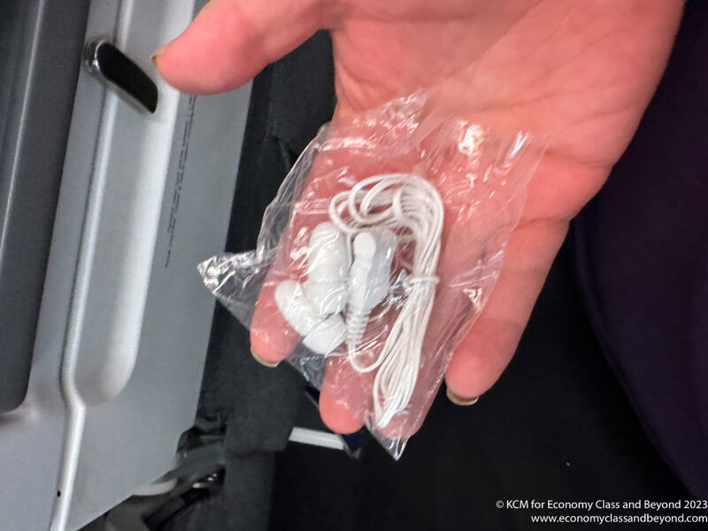 a hand holding a plastic bag with earbuds