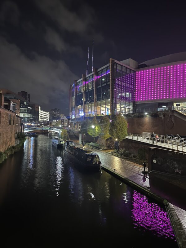 a river with a boat on it and a building with purple lights