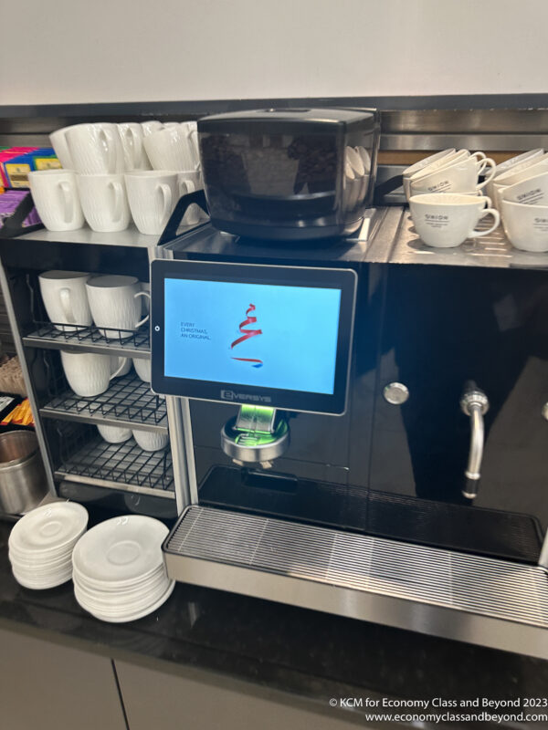 a coffee machine with a screen and cups on a shelf