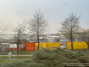 a street sign and trees by a fence