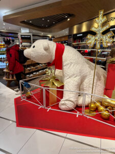 a large white bear with a scarf and gold snowflake in a store