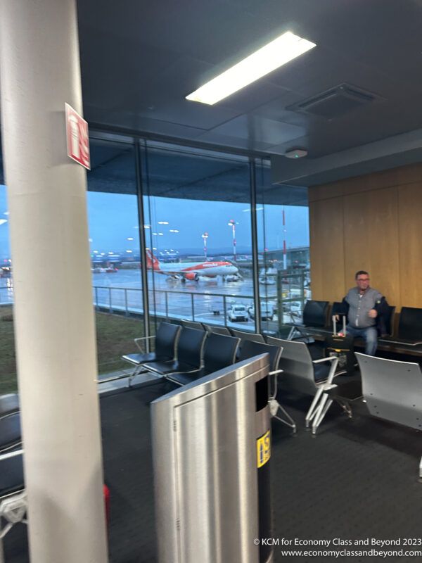 a man sitting in a waiting area with an airplane in the background