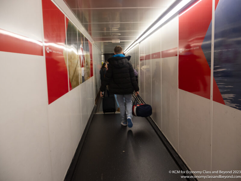 a man walking down a hallway with luggage