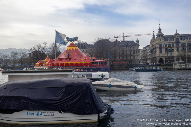 boats in a body of water with a circus tent in the background