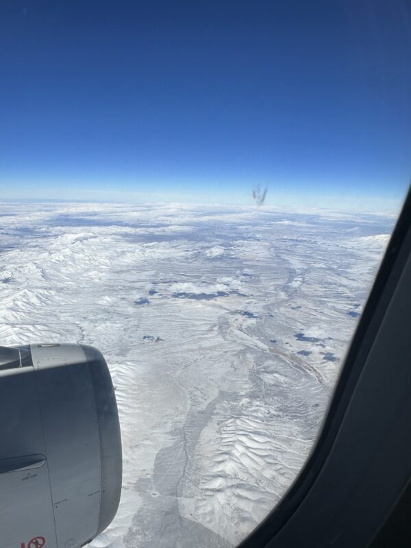 an airplane window with snow and a blue sky