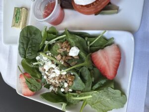 a plate of salad with strawberries and cheese
