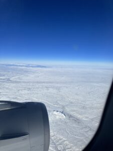 an airplane window with snow and blue sky