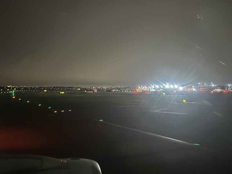 a runway at night with lights and a city in the background