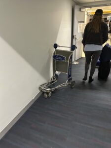 a woman walking by a luggage cart