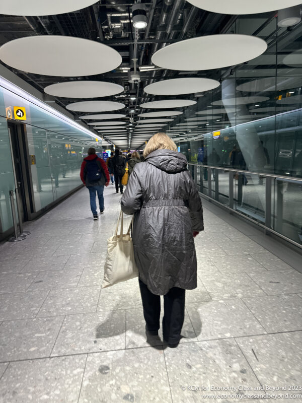 a woman in a long coat walking down a walkway