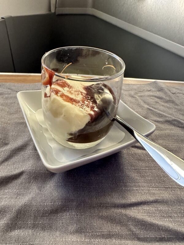 a glass cup with ice cream and a spoon on a plate