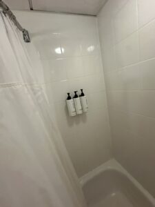 a shower with white tile and white shower curtain