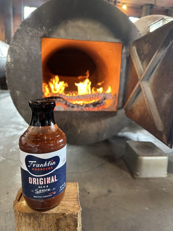a bottle of hot sauce in front of a wood stove