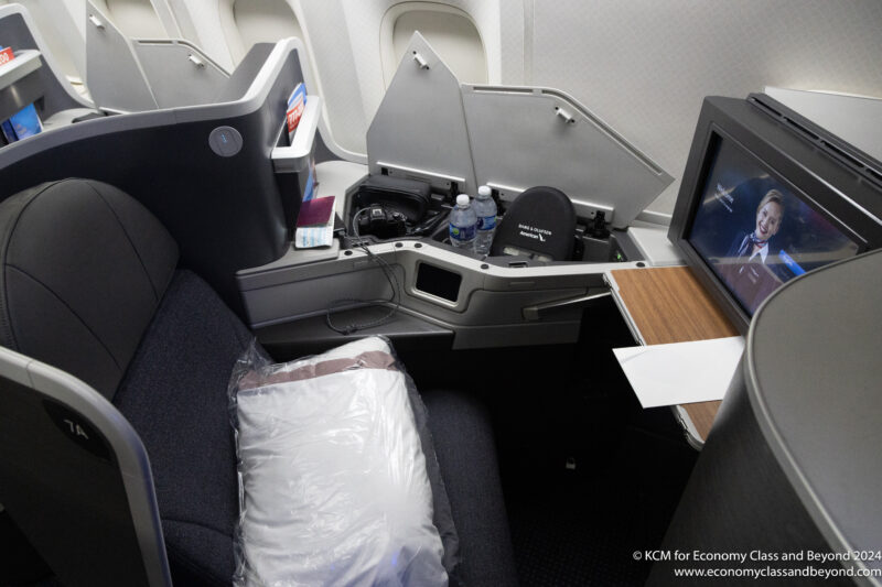 a seat in an airplane with a tv and a chair