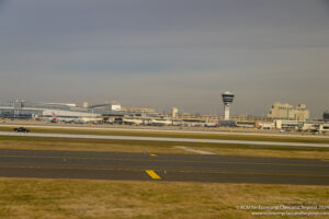an airport runway with a tower and buildings in the background