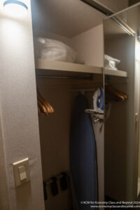 a closet with ironing board and swingers