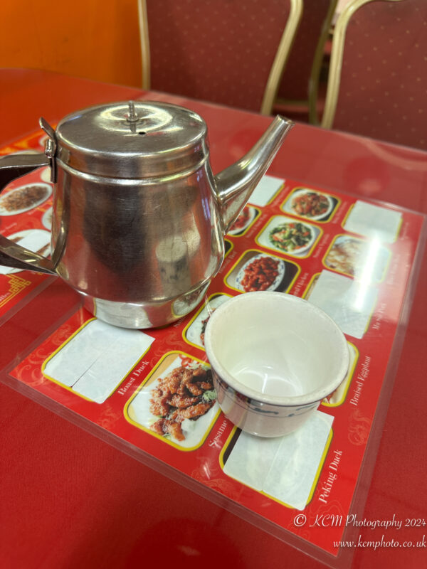 a silver teapot and a cup on a red table