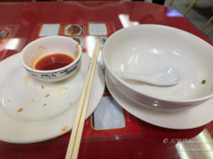 a bowl and bowl with sauce and chopsticks on a red table
