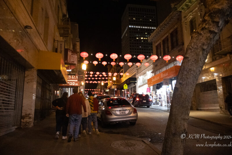 a group of people walking on a street with red lanterns